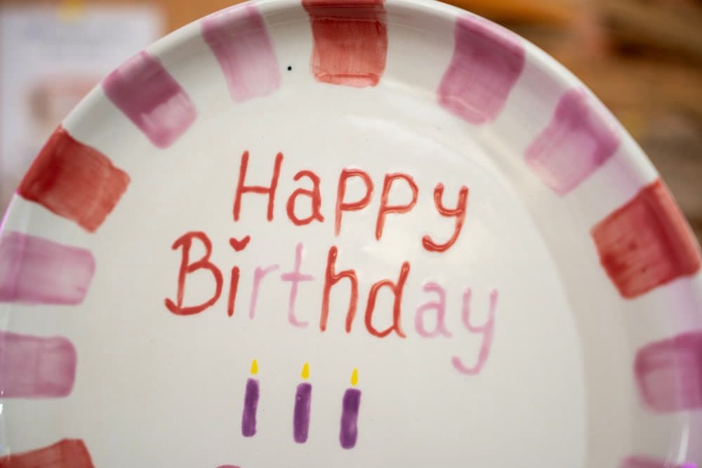 Bemalter Keramikteller mit der Aufschrift Happy Birthday und drei gemalten Kerzen